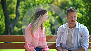 Angry woman looking at boyfriend sitting park bench, couple conflict, quarrel