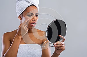 Angry woman looking at mirror, found pimple on her face