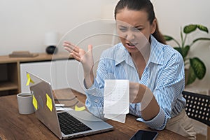 Angry woman looks at document with bank accounts frustrated by big utility bill sitting in office