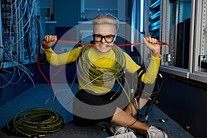 Angry woman maintenance worker biting wire while sitting in server room