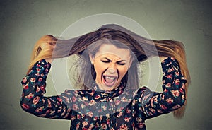 Angry woman pulling her hair out screaming