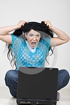 Angry woman pulling out hair in front of laptop