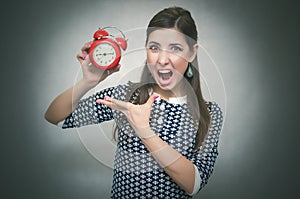 Angry woman with red alarm clock. Oversleep. Late at work or school lesson. photo