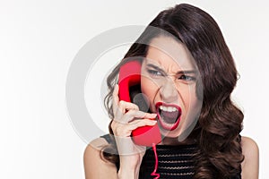 Angry woman in retro style screaming and talking on telephone