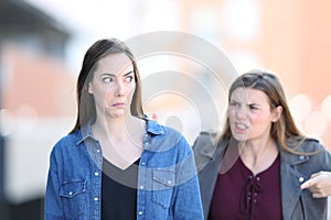 Angry woman scolding her confused friend in the street
