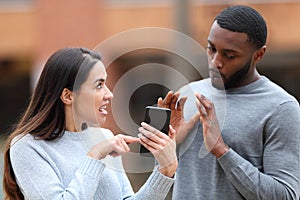 Angry woman scolding a man showing phone content