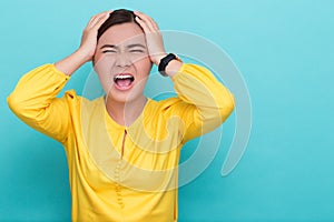 Angry woman screaming out and pulling her hair over background