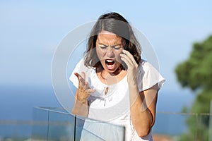 Angry woman shouting calling on phone in a balcony