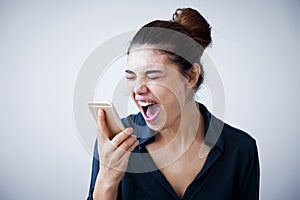 Angry woman shouting on phone on gray background