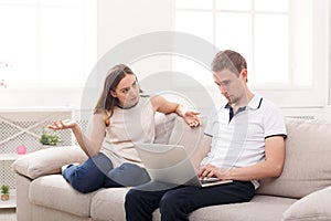 Angry woman sitting while husband using laptop