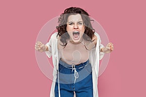 Angry woman standing arguing with somebody, clenched fists, screaming with hate and aggression.