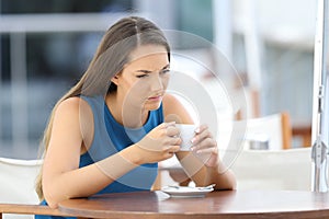 Angry woman thinking in a coffee shop terrace