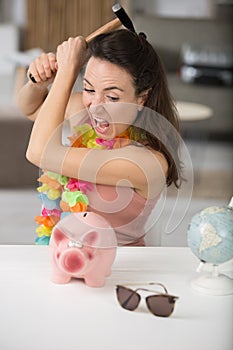 angry woman trying to break piggy bank