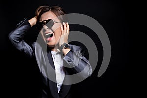 Angry woman wearing sun glasses screaming out and pulling her hair over background