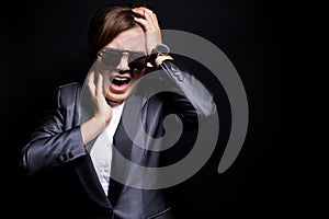 Angry woman wearing sun glasses screaming out and pulling her hair over background