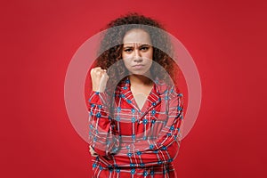 Angry young african american girl in pajamas homewear posing resting at home isolated on red wall background studio