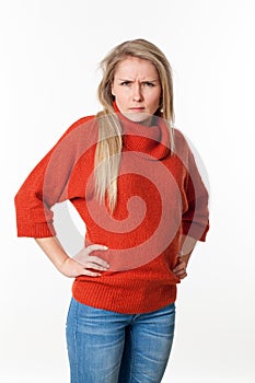 Angry young blond woman with hands on both hips staring