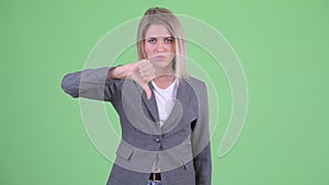 Angry young blonde businesswoman giving thumbs down