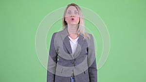 Angry young blonde businesswoman pointing at camera