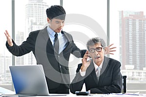 Angry young boss yelling at senior employee, business concept, Asian businessman