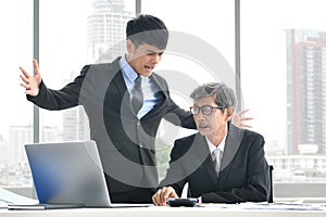 Angry young boss yelling at senior employee, business concept, Asian businessman