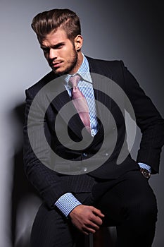 Angry young business man in classic suit and tie sitting