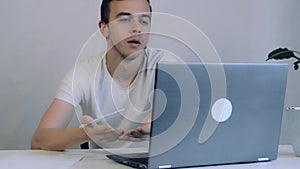 Angry Young Business man talking on video conference online in office. Worker having video call on laptop computer. Male professio