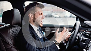 Angry young businessman driving alone in his new car