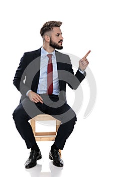 Angry young businessman pointing finger to side and blaming