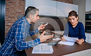 Angry young couple arguing by credit card debts