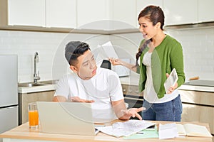 Angry young couple arguing by their many debts at home. Financial family problems concept