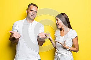 Angry young couple are shouting at each other on yellow background