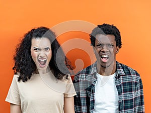 Angry Young Couple Yelling On Orange Background