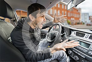 Angry young driver is driving a car and shouting photo