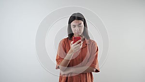 Angry young girl with cell phone receives bad message. Orange ochre shirt