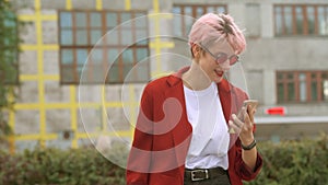 Angry young girl yells on a cell phone and typing text on a smartphone outdoor in the city street