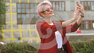 Angry young girl yells on a cell phone and typing text on a smartphone outdoor in the city street