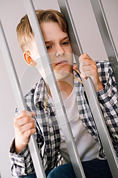 Angry young guy sitting on the steps leans on the handrails.