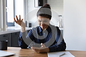 Angry young indian female holding phone disappointed losing internet signal