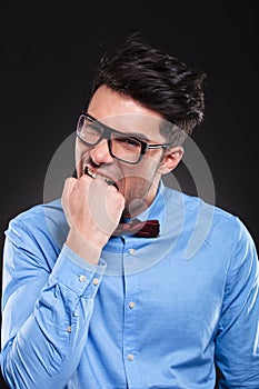 Angry young man biting his fist and staring forward