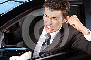 Angry young man clenching his fist, sitting in new car photo
