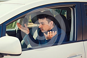 Angry young man driver, pissed off shaking hands and shrugging shoulders, has problems with the car