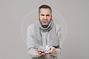 Angry young man in gray sweater, scarf isolated on grey wall background. Healthy lifestyle, ill sick disease treatment