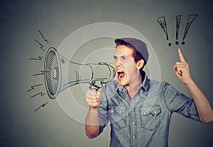 Angry young man holding screaming in megaphone