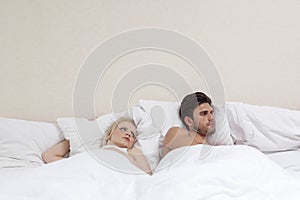 Angry young man ignoring woman in bed photo