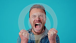 Angry young man shouting against blue background