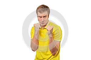 Angry young man in yellow T-shirt ready to fight with fists isolated on white background