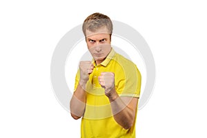 Angry young man in yellow T-shirt ready to fight with fists isolated on white background