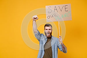 Angry young protesting man hold protest sign broadsheet placard on stick clenching fist scream isolated on yellow