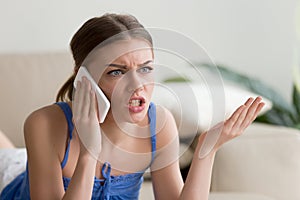 Angry young woman arguing talking on cell phone at home